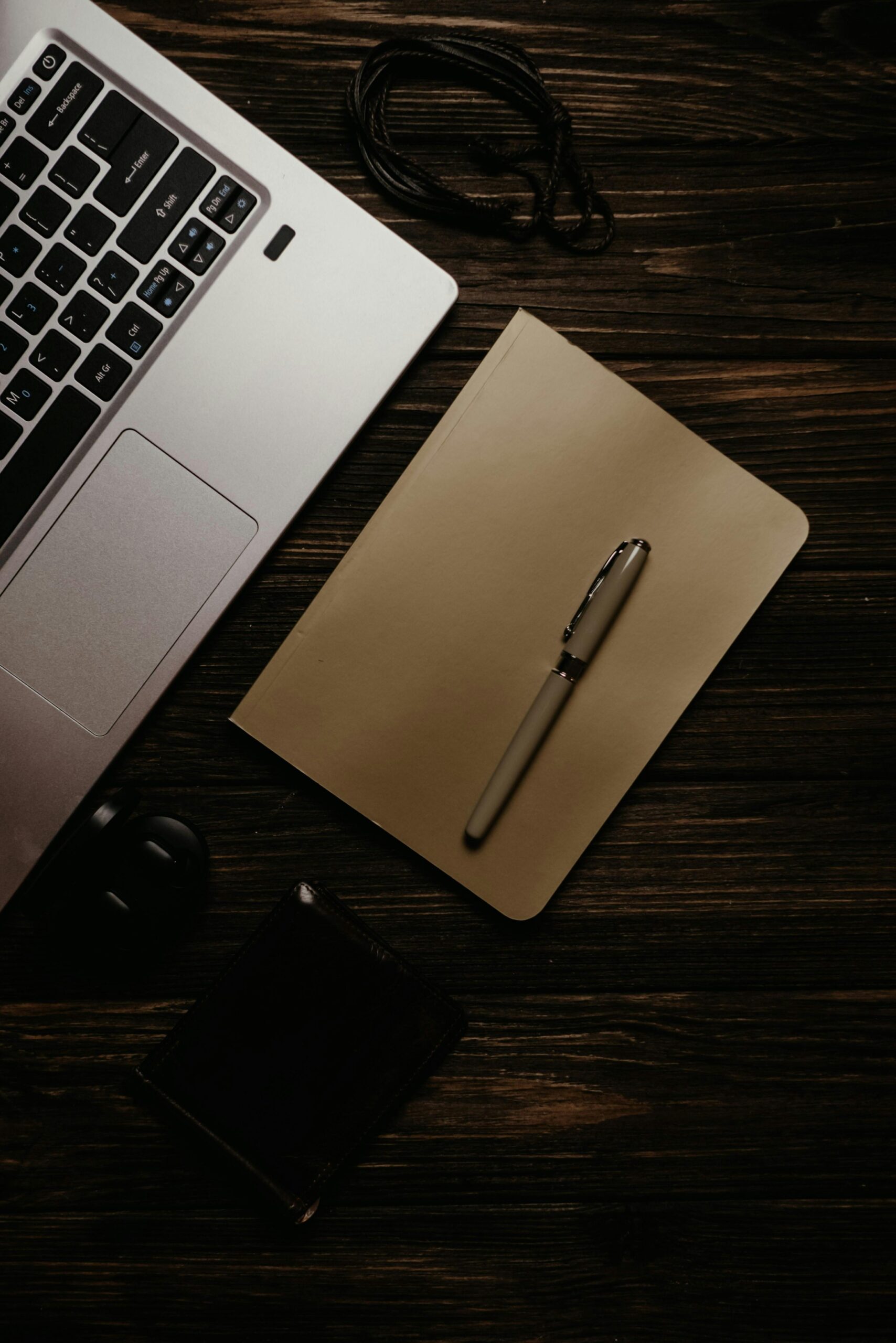 A warm, inviting workspace featuring a laptop, notebook, and pen on a wooden surface.